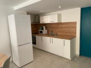 een keuken met witte kasten en een witte koelkast bij Appartement climatisé avec cour en centre ville in Carpentras