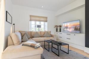 a living room with a couch and a tv at NEU! Ferienhaus Sylt 44 mit eigenem Strandkorb am Strand in Wenningstedt