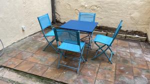 vier blauwe stoelen en een glazen tafel op een stoep bij Appartement climatisé avec cour en centre ville in Carpentras