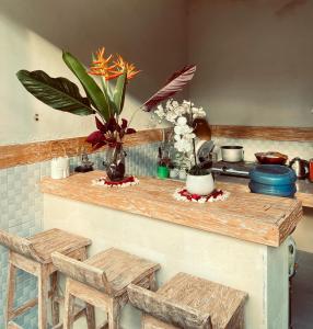 un comptoir avec deux tabourets et une table avec des fleurs dans l'établissement Ubud River Campuhan Villa, à Ubud