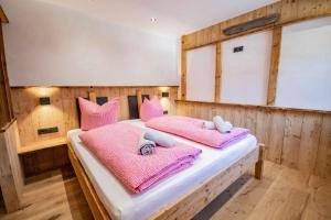 1 dormitorio con 1 cama con mantas y almohadas rosas en Peerfect Ferienwohnungen, en Navis