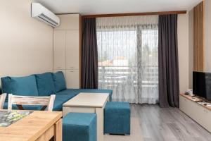 sala de estar con sofá azul y ventana en City Apartments 2 en Velingrado