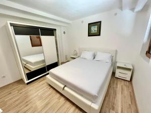 a white bedroom with a bed and a mirror at Apartments Family in Tivat