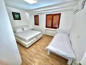 ein weißes Schlafzimmer mit einem Bett und einem Fenster in der Unterkunft Apartments Family in Tivat