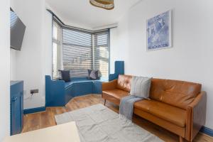 a living room with a brown leather couch and a window at Blackpool Lodge Apartments in Blackpool