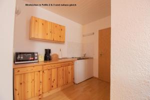 cocina con armarios de madera y nevera blanca en Dünenhaus Fewos - Zum Strand 50m en Ueckeritz