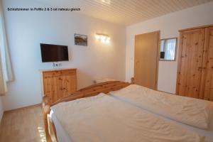 a bedroom with a bed and a flat screen tv at Dünenhaus Fewos - Zum Strand 50m in Ueckeritz