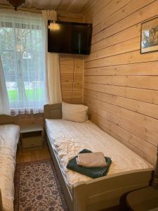 a small room with a bed and a tv on the wall at Atostogų būstas in Kurėnai