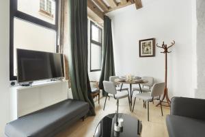 uma sala de estar com uma televisão e uma mesa com cadeiras em Apartment Saint Germain des Prés by Studio prestige em Paris