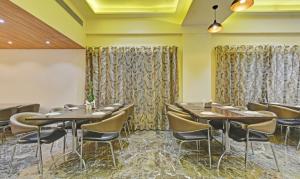a dining room with tables and chairs and curtains at Hotel Mandovin Near Railway Station in Udaipur