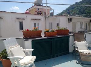 a balcony with chairs and potted plants on it at Appartamento Iasolino in Ischia