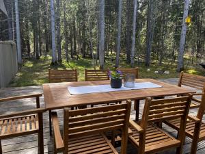 a wooden table and chairs on a deck with trees at Villa Hausma in Hiiumaa