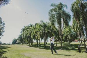 a man throwing a frisbee in a park with palm trees at Hotel & Golfe Clube dos 500 in Guaratinguetá