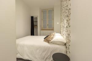 a bedroom with a white bed and a black chair at Appartement R1 T2 Rodez Centre Historique in Rodez