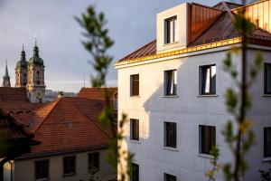 a white building with a clock tower in the background at EH Apartments Merkur in St. Gallen