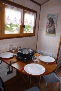 einen Holztisch mit Tellern auf einem Zimmer in der Unterkunft Roulotte La Marmotte in Poinson-lès-Fays