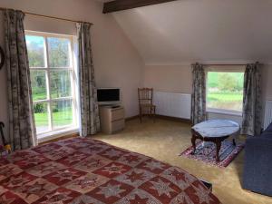 um quarto com uma cama e uma televisão e duas janelas em The Coach House em Tilston