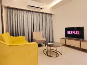 ein Wohnzimmer mit einem TV, einem Stuhl und einem Tisch in der Unterkunft OSI Apartments BKC Kurla West in Mumbai