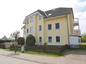 una casa gialla con una recinzione di fronte di Bernsteinhaus Wohnung 3 mit 2 Balkonen & Kamin a Kolpinsee