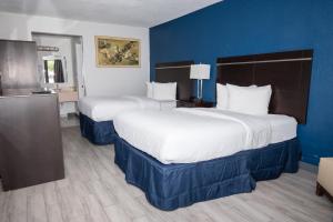 2 Betten in einem Hotelzimmer mit blauen Wänden in der Unterkunft Developer Inn Orlando North, a Baymont by Wyndham in Orlando