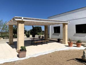 a pavilion with a table and a bench in front of a building at Fraschi Countryhouse in Carpignano Salentino