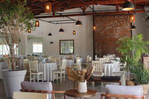 a restaurant with white tables and chairs and potted plants at Pousada Estancia Canastra in Delfinópolis