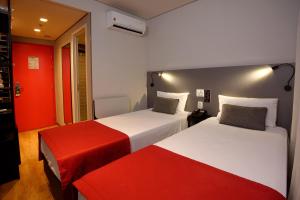 duas camas num quarto com vermelho e branco em Golden Tower Express Berrini by Fênix Hotéis em São Paulo