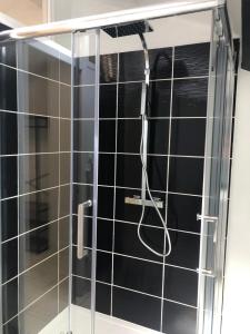 een douche in een badkamer met zwarte tegels bij Maison de ville au coeur de Ribérac in Ribérac