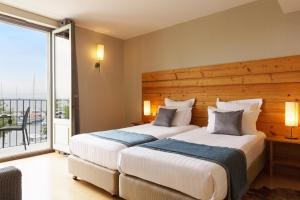 two beds in a hotel room with a balcony at Hôtel Le Jules Verne in Yvoire