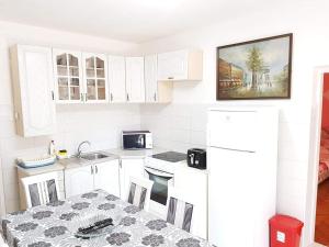 a kitchen with white cabinets and a table and a sink at Montenegro Apartments - Private Beach in Kotor