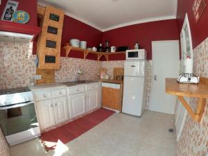 uma cozinha com electrodomésticos brancos e paredes vermelhas em Carlo's Beach Guest House em Odeceixe