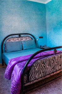 a bed in a room with a blue wall at riad lala fatima in Ouzoud