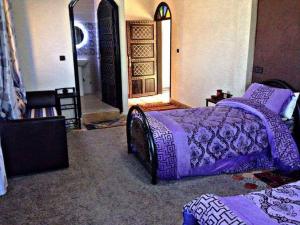 a bedroom with two beds with purple sheets and a door at riad lala fatima in Ouzoud