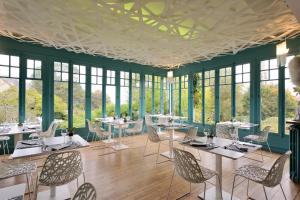 ein Esszimmer mit Tischen, Stühlen und Fenstern in der Unterkunft Ty Mad in Douarnenez