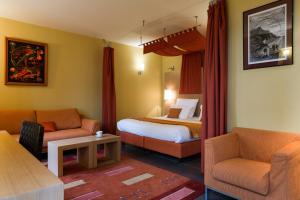 a hotel room with a bed and two chairs at Hôtel Le Jules Verne in Yvoire