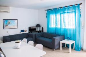 een woonkamer met een blauwe bank en een tafel bij Villa Vave in Nea Iraklia