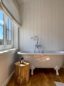 uma banheira branca na casa de banho com um toco de madeira em Ragnar Glamp Milzkalne Forest em Rauda