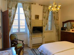 een slaapkamer met een bed, een televisie en ramen bij La Grenouille Noire in Marcillat-en-Combraille
