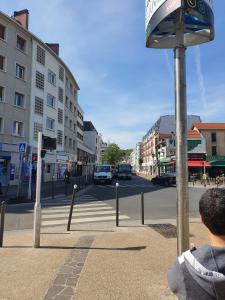 un hombre está mirando un cartel de la calle en una calle de la ciudad en Chambre privée avec clé, WIFI dans appartement (SDB, WC, Cuisine, partagés), en Juvisy-sur-Orge