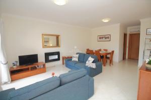 a living room with a blue couch and a tv at Apartment Garcas Lounge - By Dalma Portuguesa in Albufeira