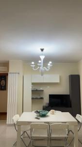 une salle à manger avec une table blanche et un lustre dans l'établissement IL DIAMANTE, appartamento elegante vicino al mare!, à Terracine