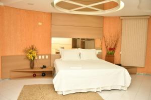 um quarto com uma grande cama branca com almofadas brancas em Troodon Park Hotel em Sousa