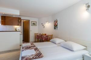 a room with a white bed and a kitchen at Lorena Apartment Dubrovnik in Dubrovnik