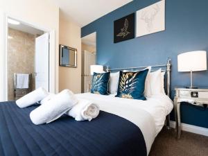 a bedroom with a large bed with blue walls at Scarborough Stays - Luxury Townhouse Ideal for large groups - HOT TUB in Scarborough