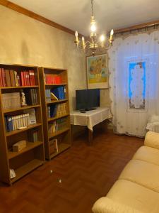 LuniにあるCASA DEGLI ZII appartamento Letiziaのリビングルーム(デスク、テレビ、本棚付)