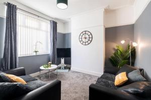 格里姆斯比的住宿－Contractor & Leisure & Garden & Central Location，客厅配有沙发和墙上的时钟