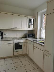 a kitchen with white cabinets and a stove top oven at Entspannt Wohnen - vor den Toren Lübecks in Stockelsdorf