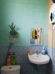 a bathroom with a sink and a toilet and a mirror at Agimats Crib Palawan in Puerto Princesa City