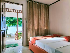 a bedroom with a bed and a sliding glass door at Orange Pearl Beach Resort in El Nido