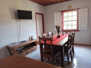 een eetkamer met een tafel en stoelen en een televisie bij Casa do Aconchego in Tiradentes